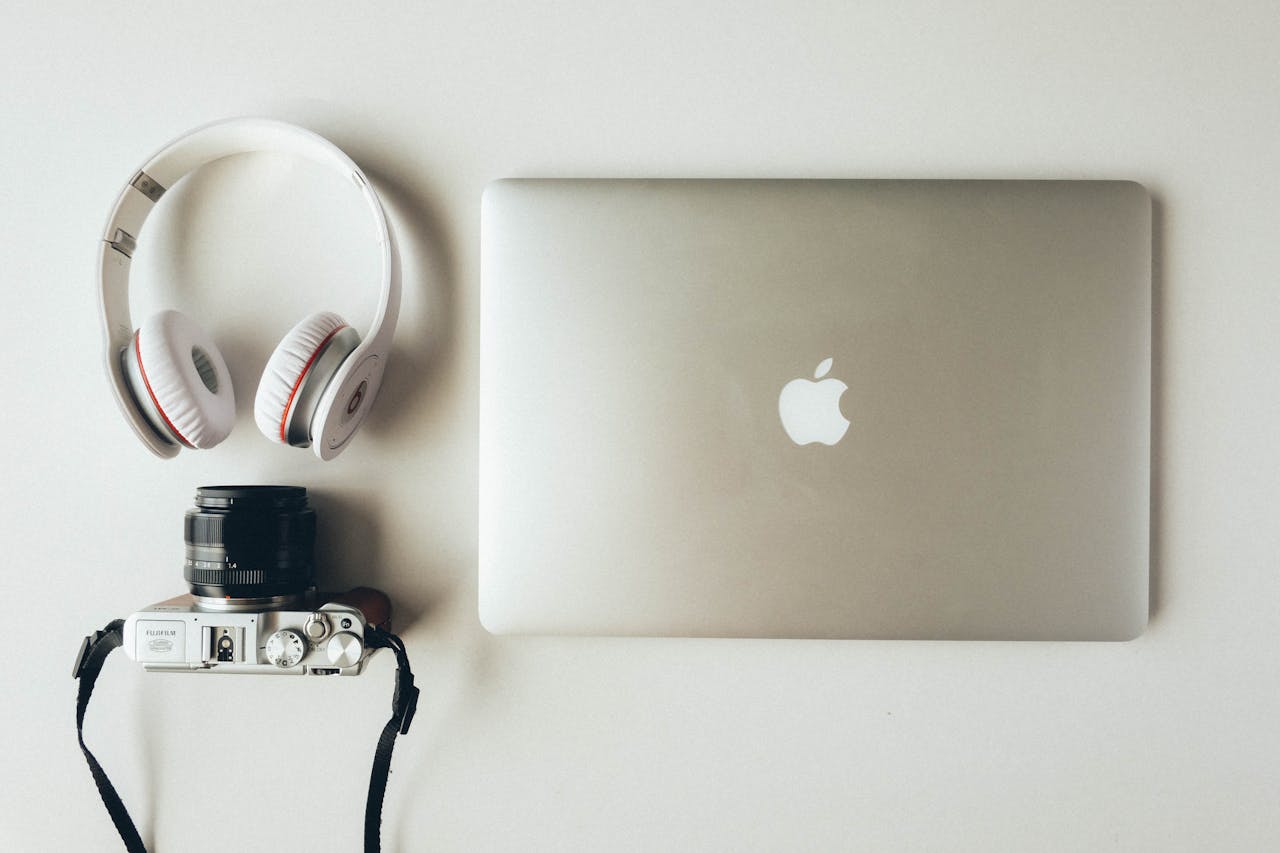 Home A modern flat lay of a laptop, headphones, and a camera showcasing tech essentials.