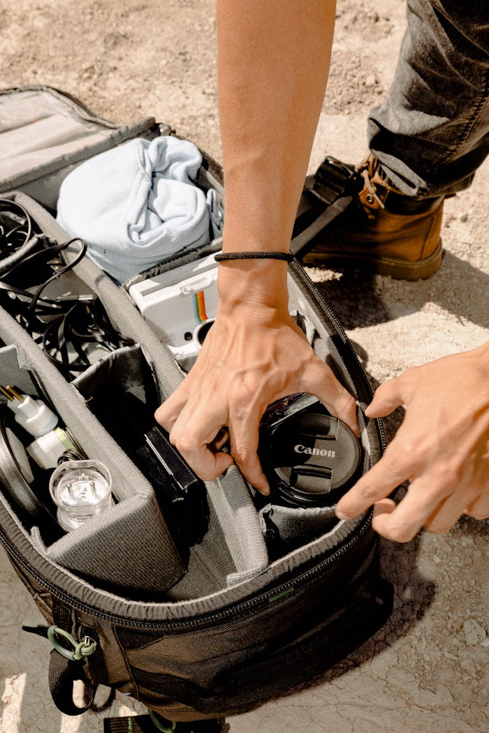 Close-up of hands packing camera bag with gear for an outdoor photoshoot.